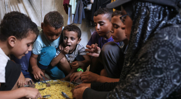 صورة من غزة .. أم تتقاسم وجبة مع أطفالها بعد ساعات انتظار قاسية